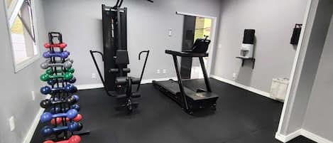 Un gimnasio en casa con barra de dominadas, banco de pesas y cinta de correr.