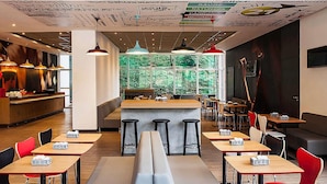 A modern restaurant interior with a central bar, booths, and high tables. - Ibis Juiz De Fora (Juiz de Fora)