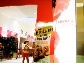 A restaurant interior with a promotional poster, wooden furniture, and a potted plant. - Ibis Juiz De Fora (Juiz de Fora)