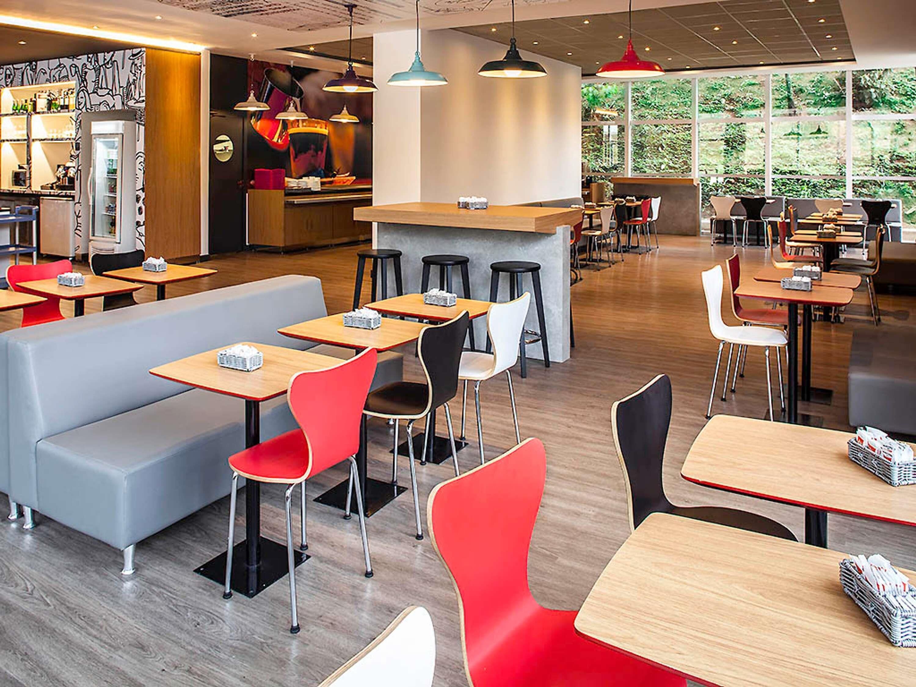 A modern cafe with multiple seating areas, including booths and tables, and a bar counter.