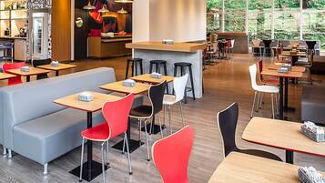 A modern cafe with multiple seating areas, including booths and tables, and a bar counter.
