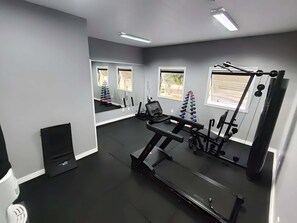 Ett gym med träningsredskap, ett löpband och en spegel.