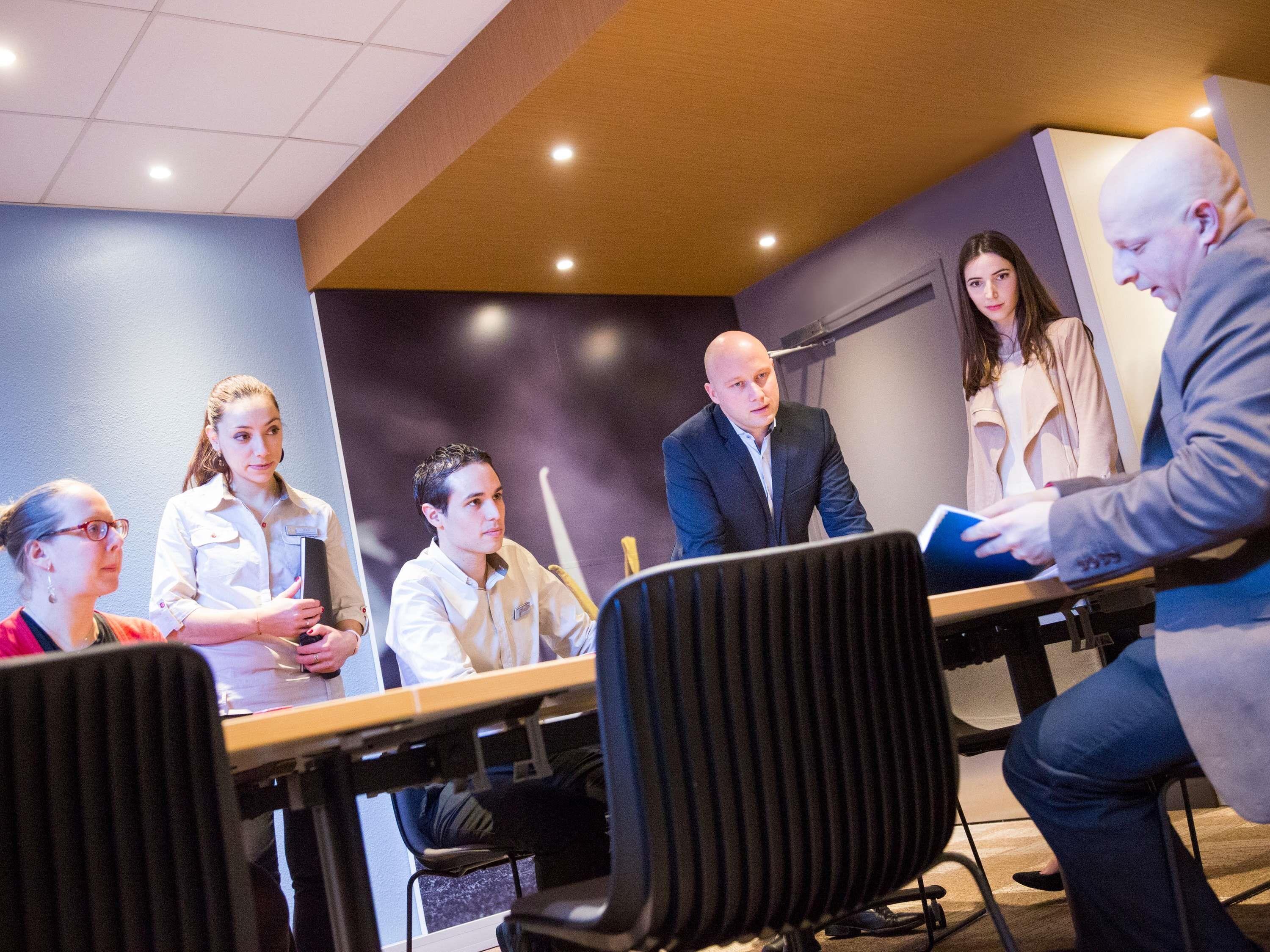 A conference room with a long table, chairs, and a whiteboard.