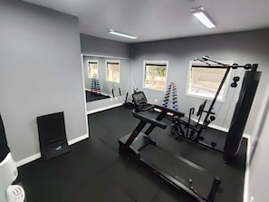 Ett gym med träningsredskap, ett löpband och en spegel.