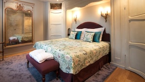 A bedroom with a large bed, a bench, a wardrobe, and a mirror.