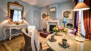 A well-appointed living room with a large mirror, a fireplace, and a round coffee table with decorative items.