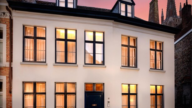 A white building with multiple windows and a dark entrance door, set against a twilight sky.