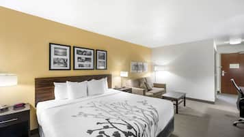 A hotel room with a large bed, a desk, a chair, and two wall-mounted lamps.