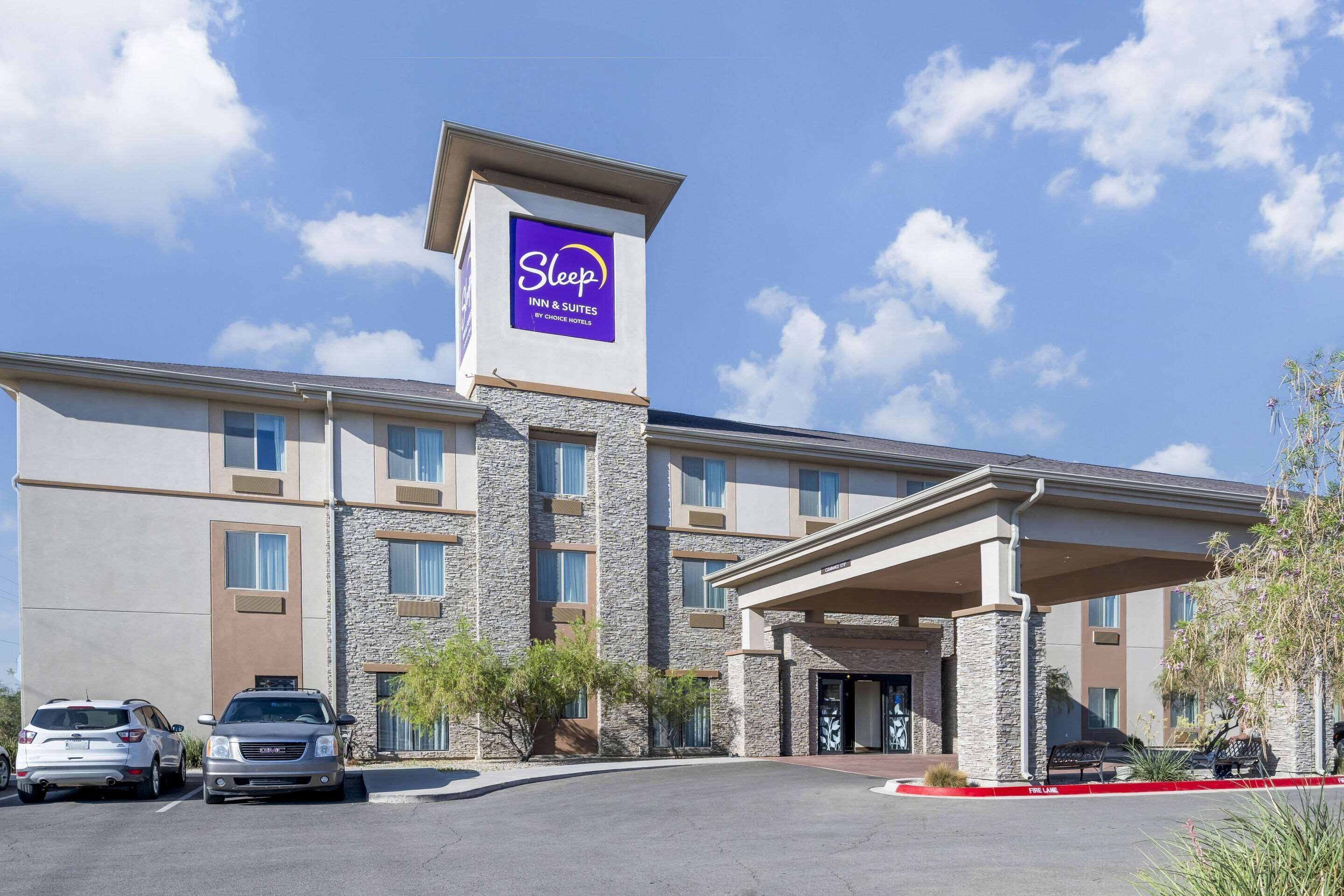 Edificio Sleep Inn & Suites con fachada de piedra, un acceso cubierto y un estacionamiento con coches.