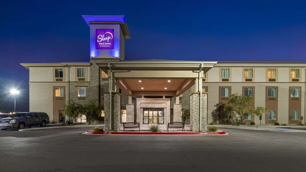A hotel entrance with a covered area, a sign for 'Sleep Inns & Suites', and a parking lot. - Sleep Inn & Suites Carlsbad Caverns Area (Carlsbad)