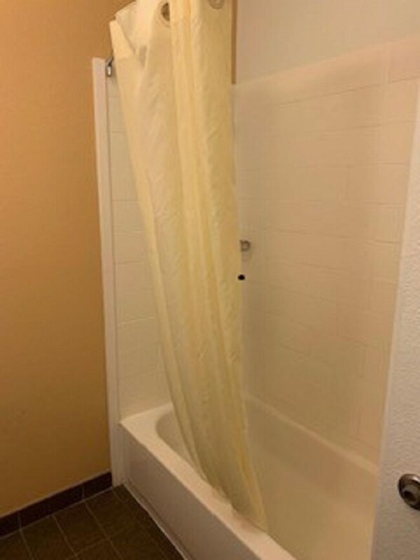 Une salle de bain avec une baignoire, un rideau de douche et des murs carrelés.