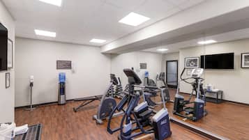 A gym with various exercise machines, a water dispenser, and a mirror reflecting the equipment.