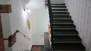 A staircase with a handrail, a wall-mounted light fixture, and a stone accent piece. - Faunele (Orosei)