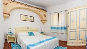 A bedroom with a bed, nightstands, a wardrobe, and a decorative archway. - Faunele (Orosei)