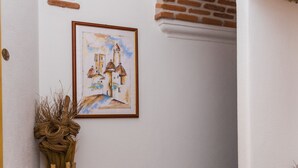 A corner of a room with a tiled floor, a framed painting on the wall, and a decorative vase. - Faunele (Orosei)