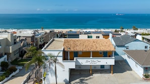 A hotel with a sign reading "Sea View Inn At The Beach" with a view of the ocean and beach in the background.