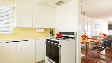 A kitchen with white cabinets, a stove, and a dining area with a table and chairs.