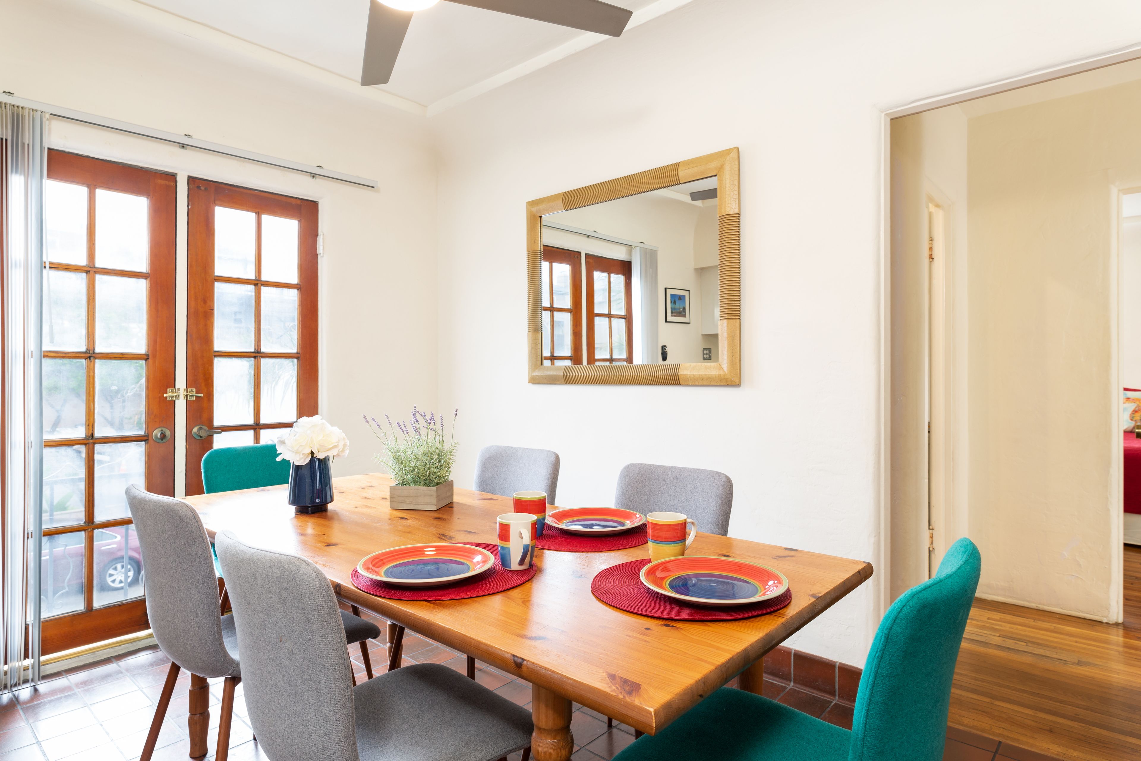 Uma área de refeições com uma mesa de madeira, quatro cadeiras e um espelho na parede.