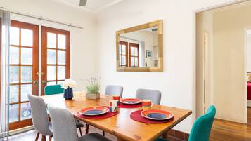 Uma área de refeições com uma mesa de madeira, quatro cadeiras e um espelho na parede.