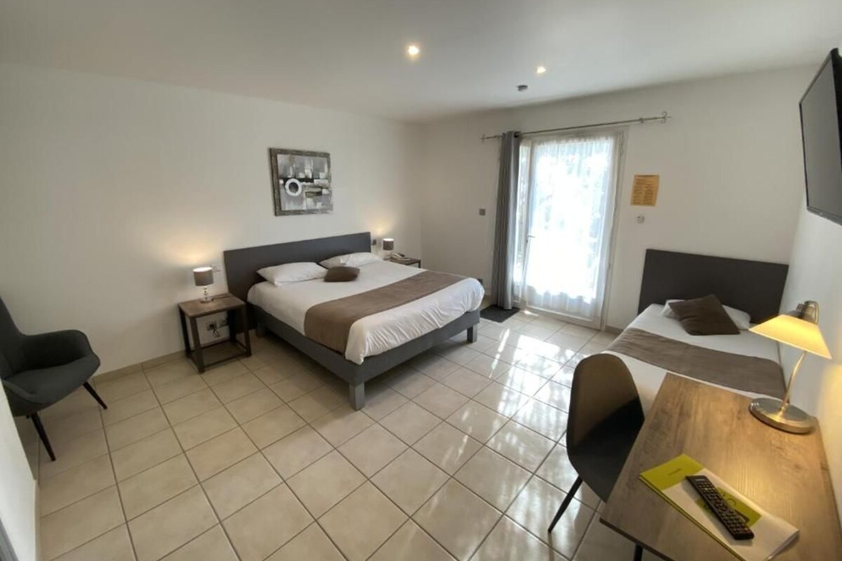 Een hotelkamer met een bed, een bureau met lamp, een stoel en een televisie.