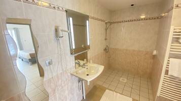 Un bagno con doccia, lavandino e specchio.