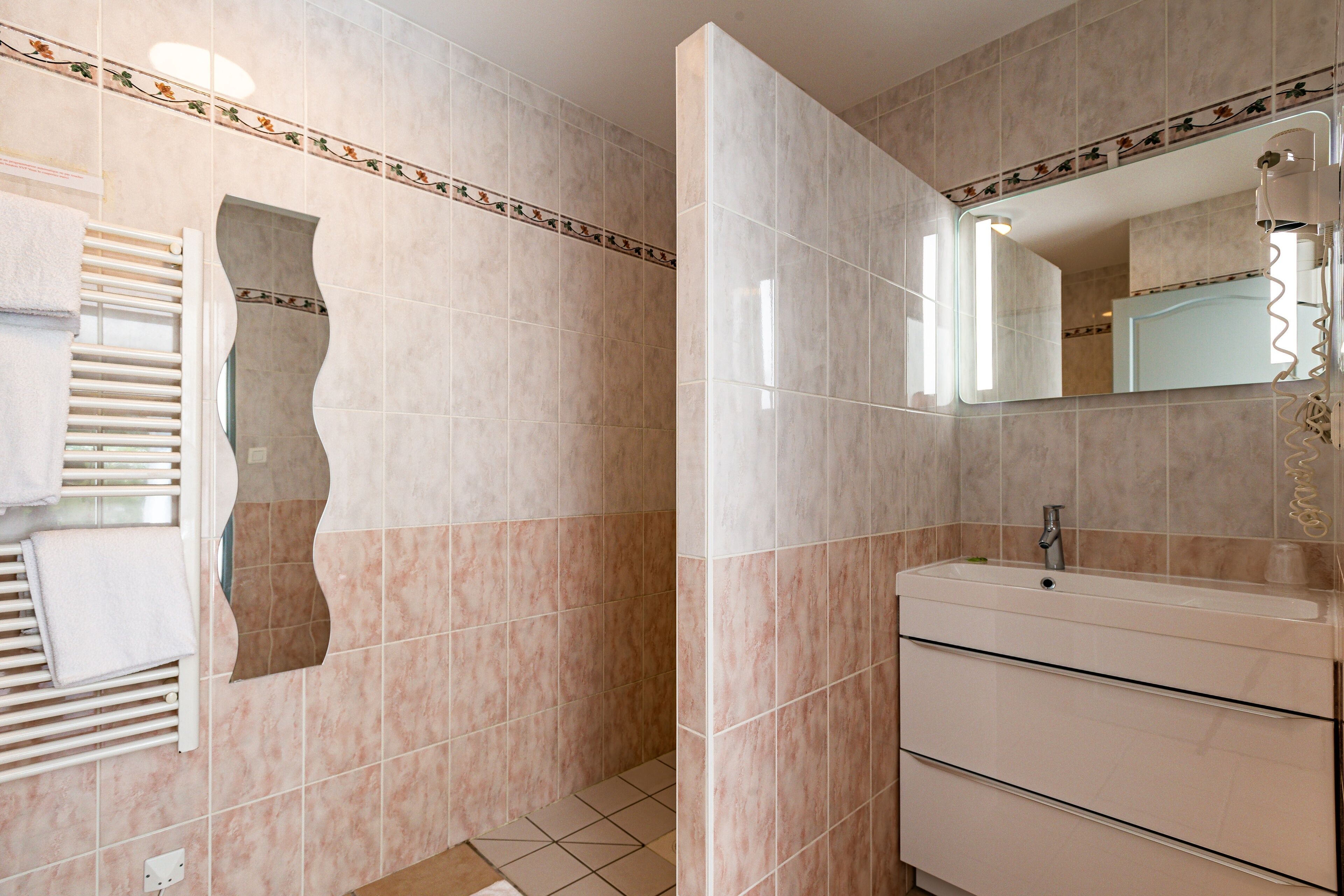 A bathroom with beige tiles, a white sink, and a towel rack.
