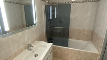 A bathroom with a sink, mirror, shower, and bathtub.
