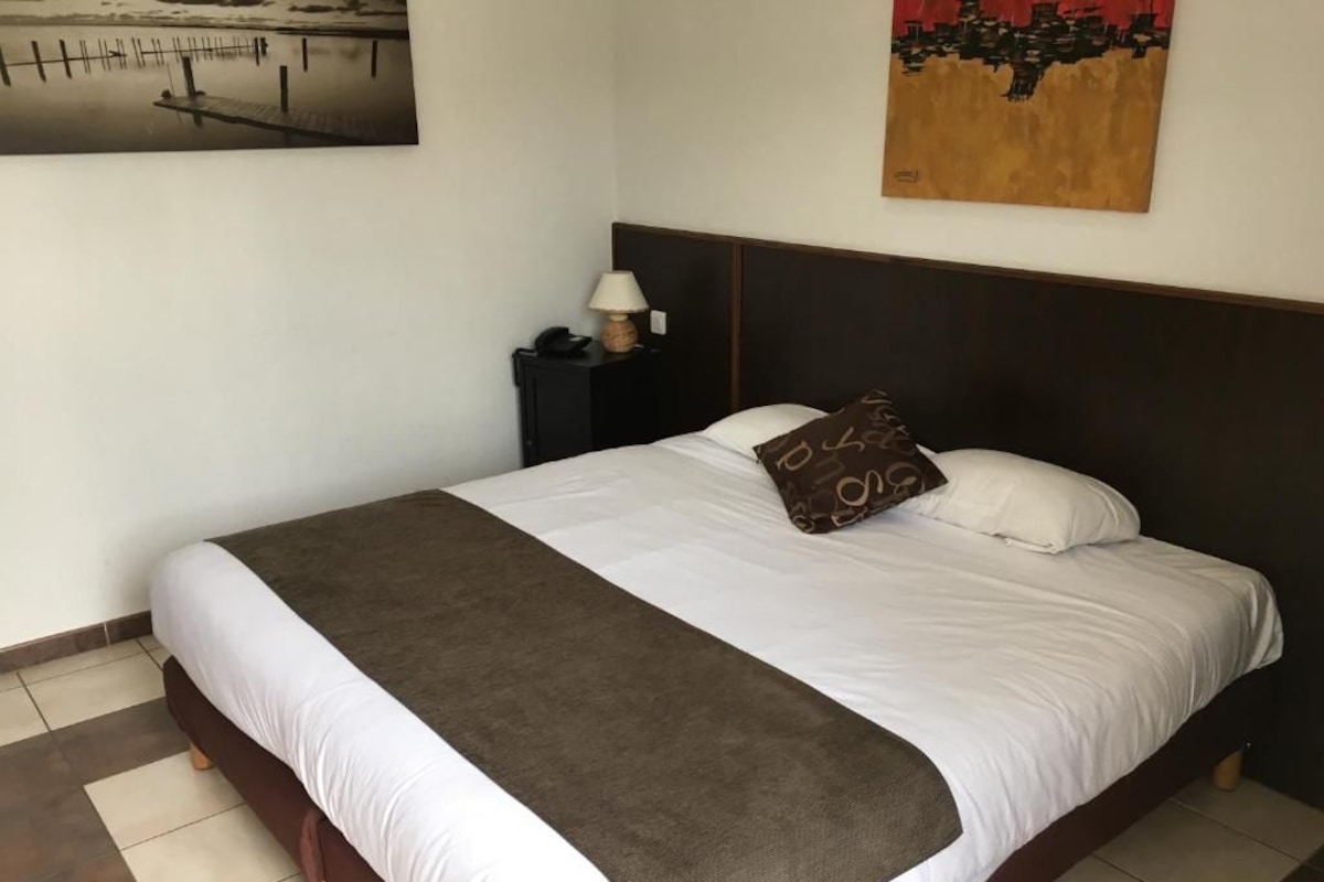 Een keurig opgemaakt bed met een bruine plaids en een kussen met een patroon.