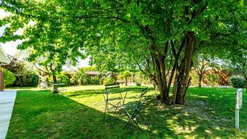 A well-maintained garden with a lawn, two green benches, and a pathway.