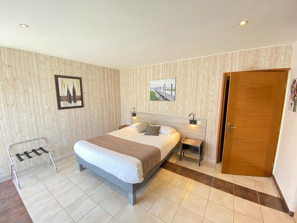 Une chambre moderne avec un grand lit, des tables de chevet, un banc et une porte en bois.