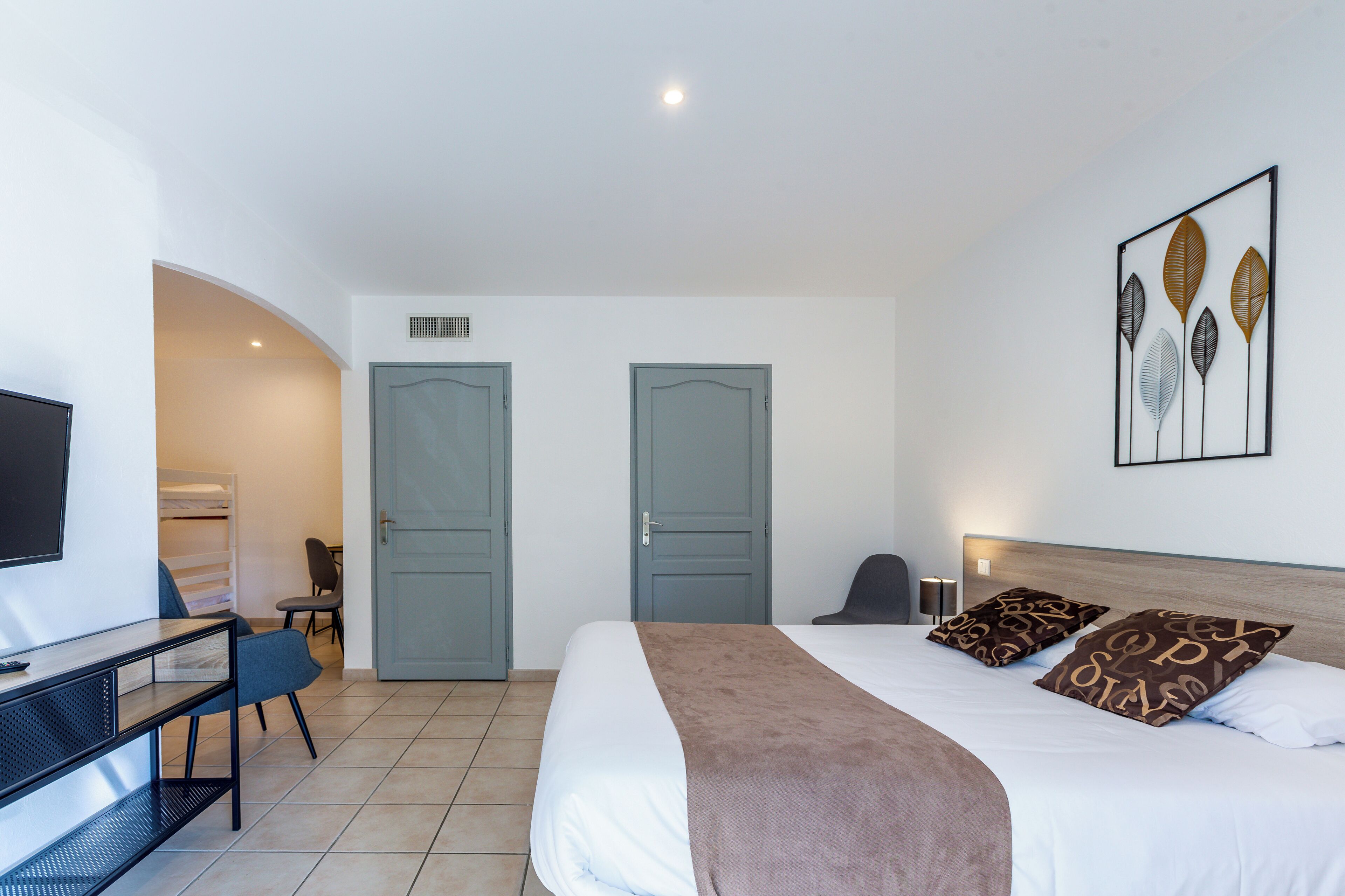 Una habitación de hotel con cama, escritorio, silla y televisión.