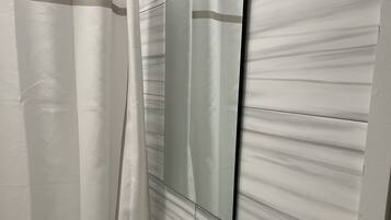 A bathroom with a shower curtain, a sink, and a mirror.