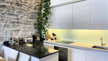 A modern kitchen with a stone wall, white cabinets, and a central island with bar stools.