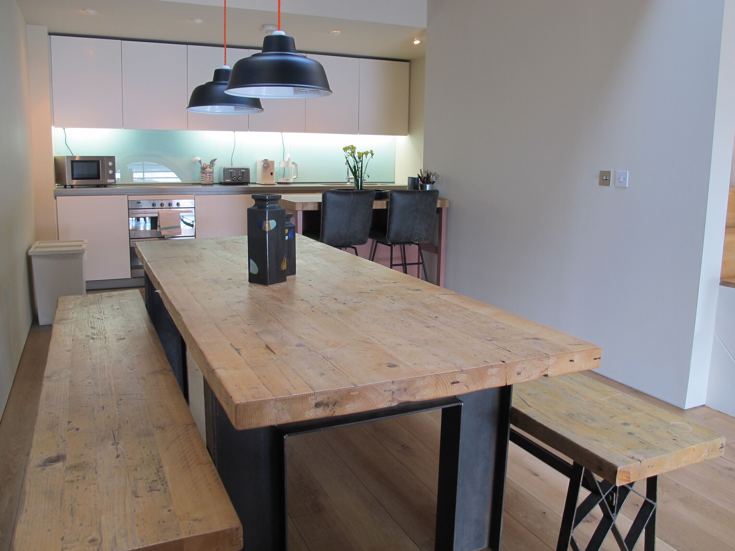 Een keuken met een houten tafel, twee hanglampen en een magnetron.