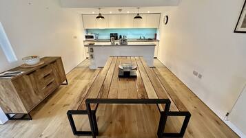 Una cocina moderna con una isla central, suelo de madera e iluminación colgante.