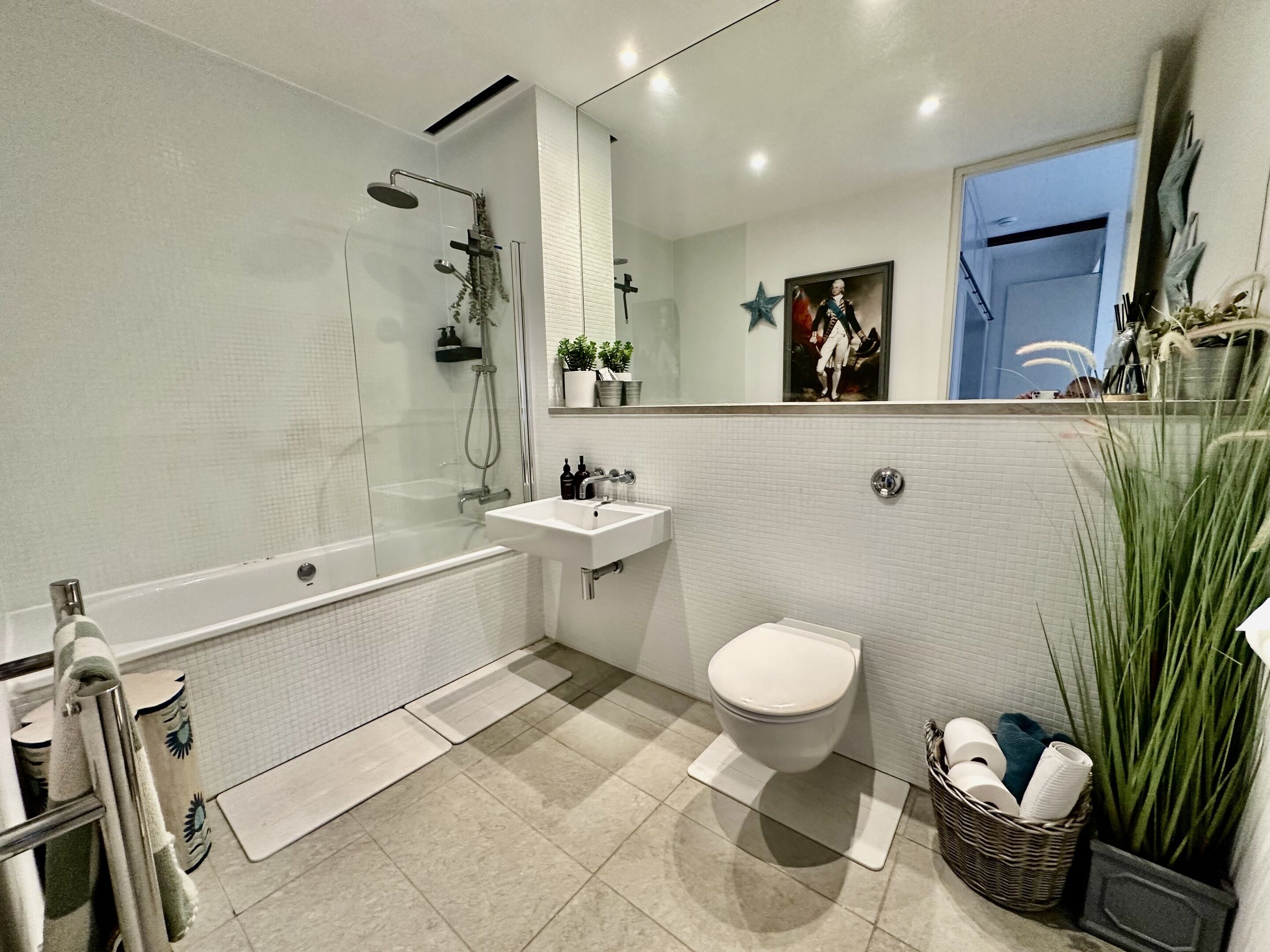 Un baño moderno con ducha de vidrio, un lavamanos blanco y un inodoro.