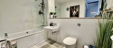 A modern bathroom with a glass-enclosed shower, a white sink, and a toilet.