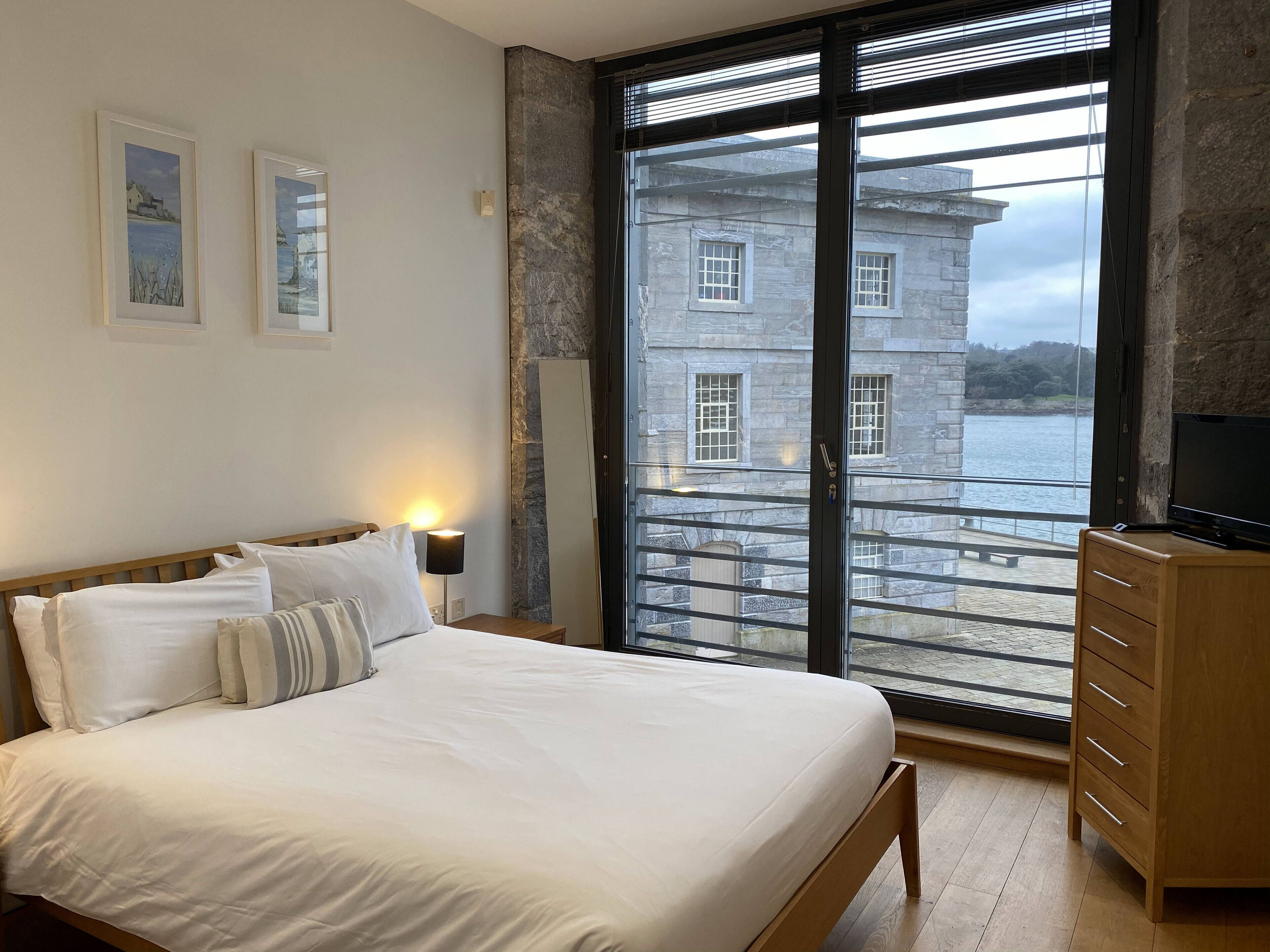 A bedroom with a bed, bedside lamp, and a dresser.