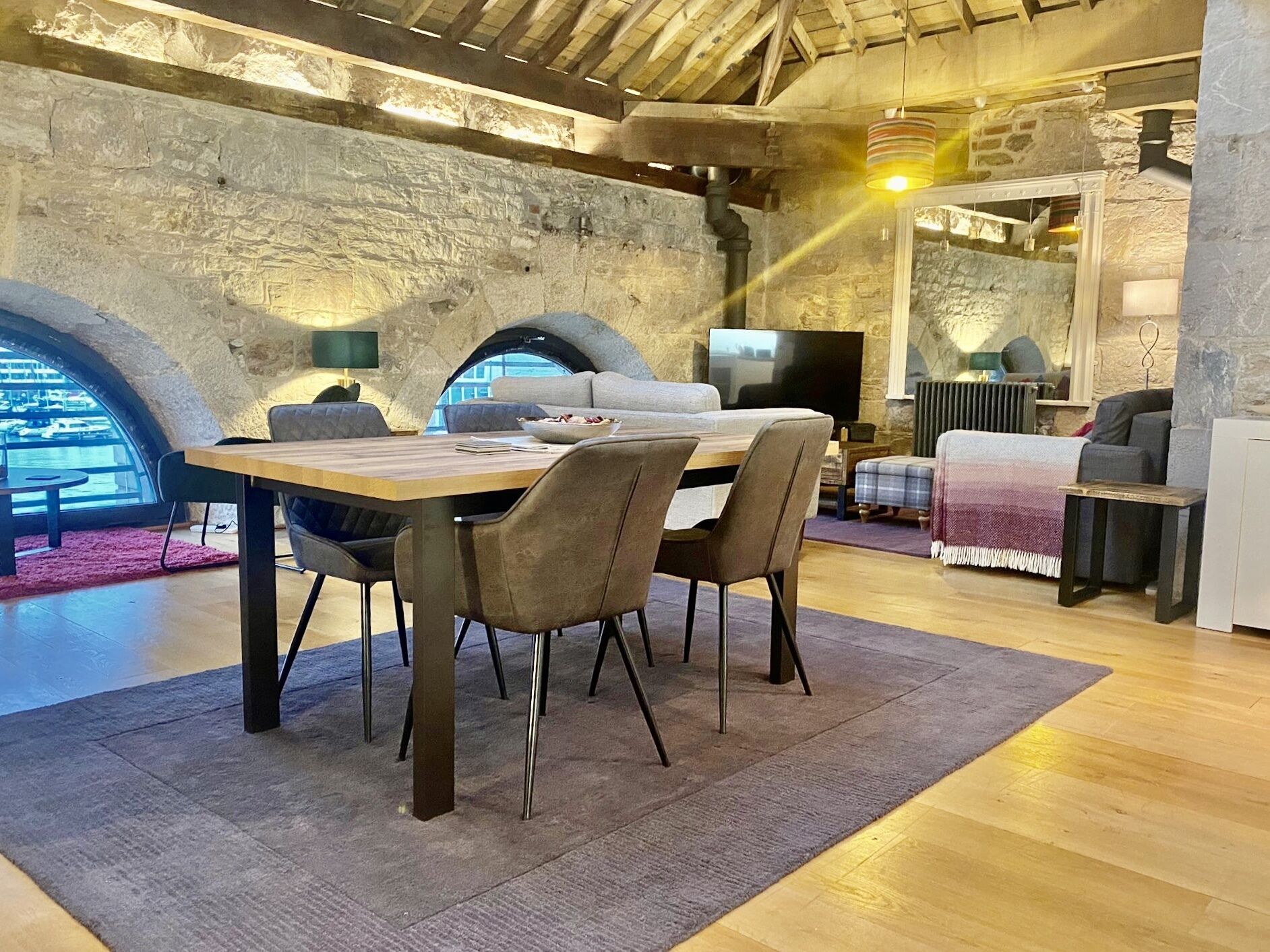 Un comedor acogedor con una mesa y sillas de madera, una pared de piedra y un televisor.