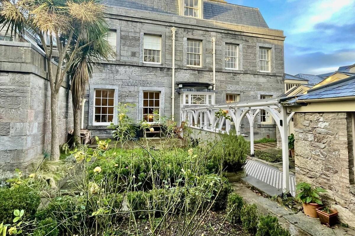 Un bâtiment en pierre doté de nombreuses fenêtres et d’une allée couverte.