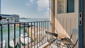 Een balkon met uitzicht op een jachthaven en gebouwen aan de overkant van het water.