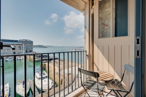 A balcony with a view of a marina and buildings across the water.