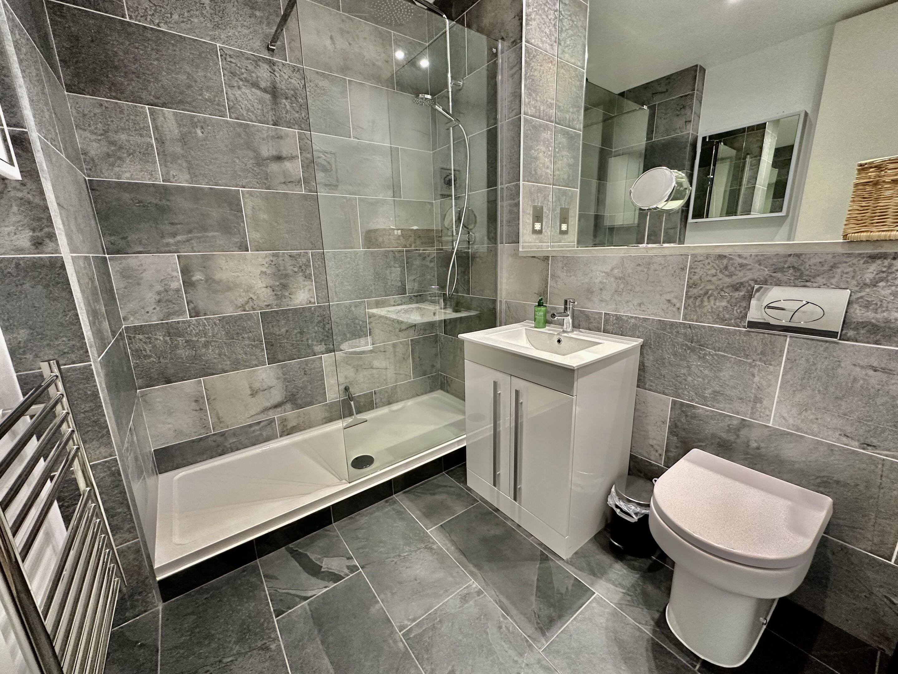 Un baño moderno con ducha envuelta en vidrio, un lavabo blanco y un inodoro.