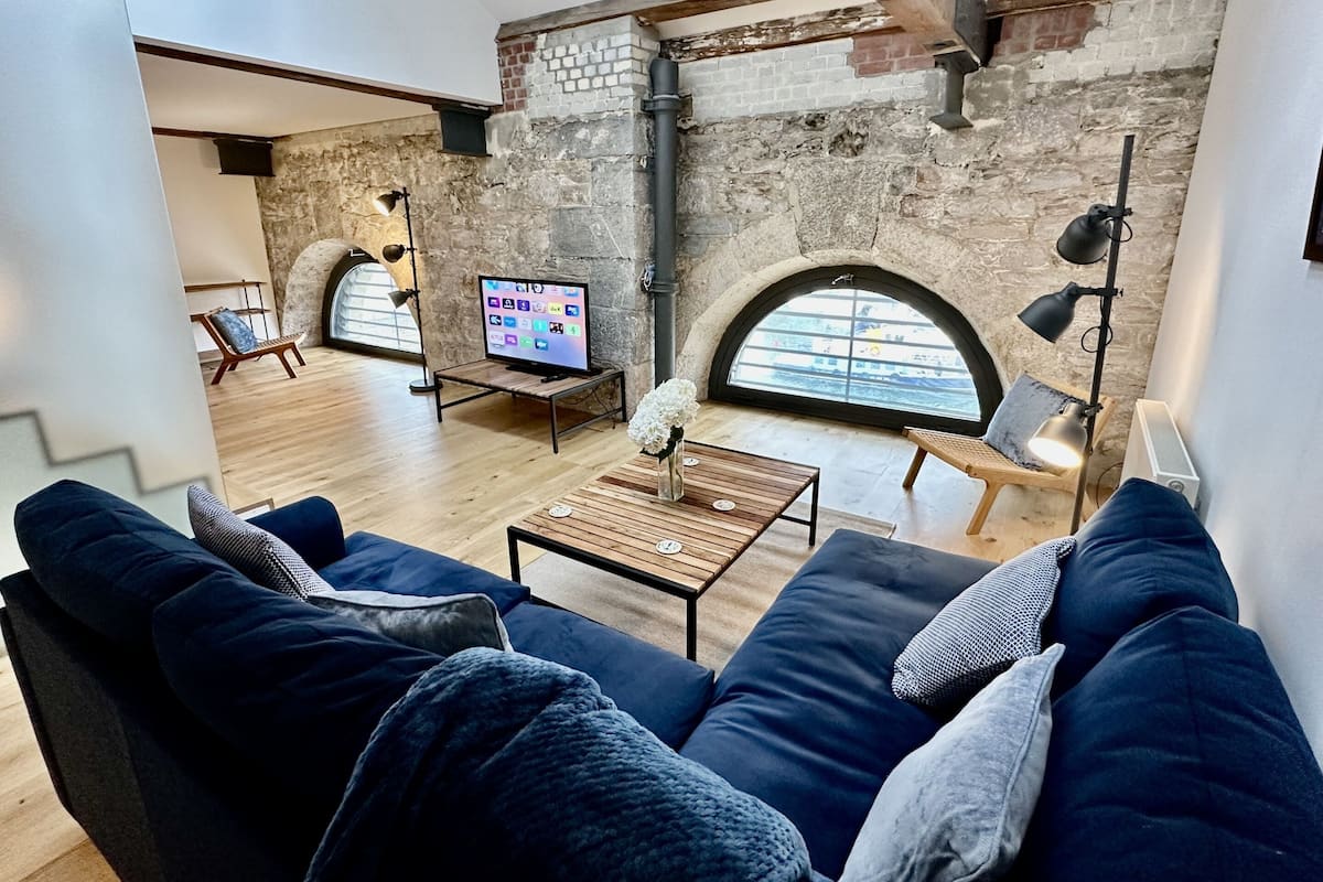 Un salon moderne avec un mur en pierre, un téléviseur, un canapé et une table basse.