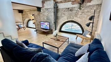 A modern living room with a stone wall, a television, a sofa, and a coffee table.