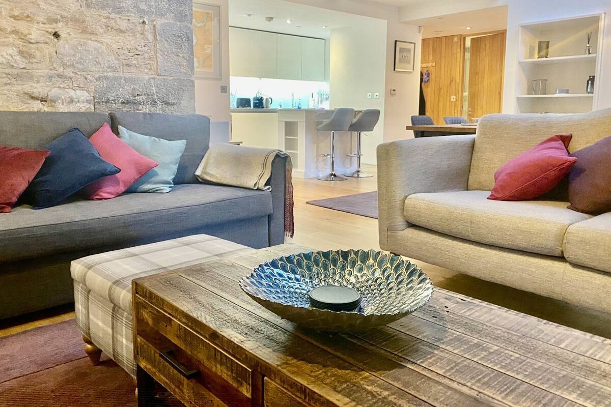 Un salon moderne avec deux canapés, une table basse agrémentée d’un vase décoratif et un mur en pierre.