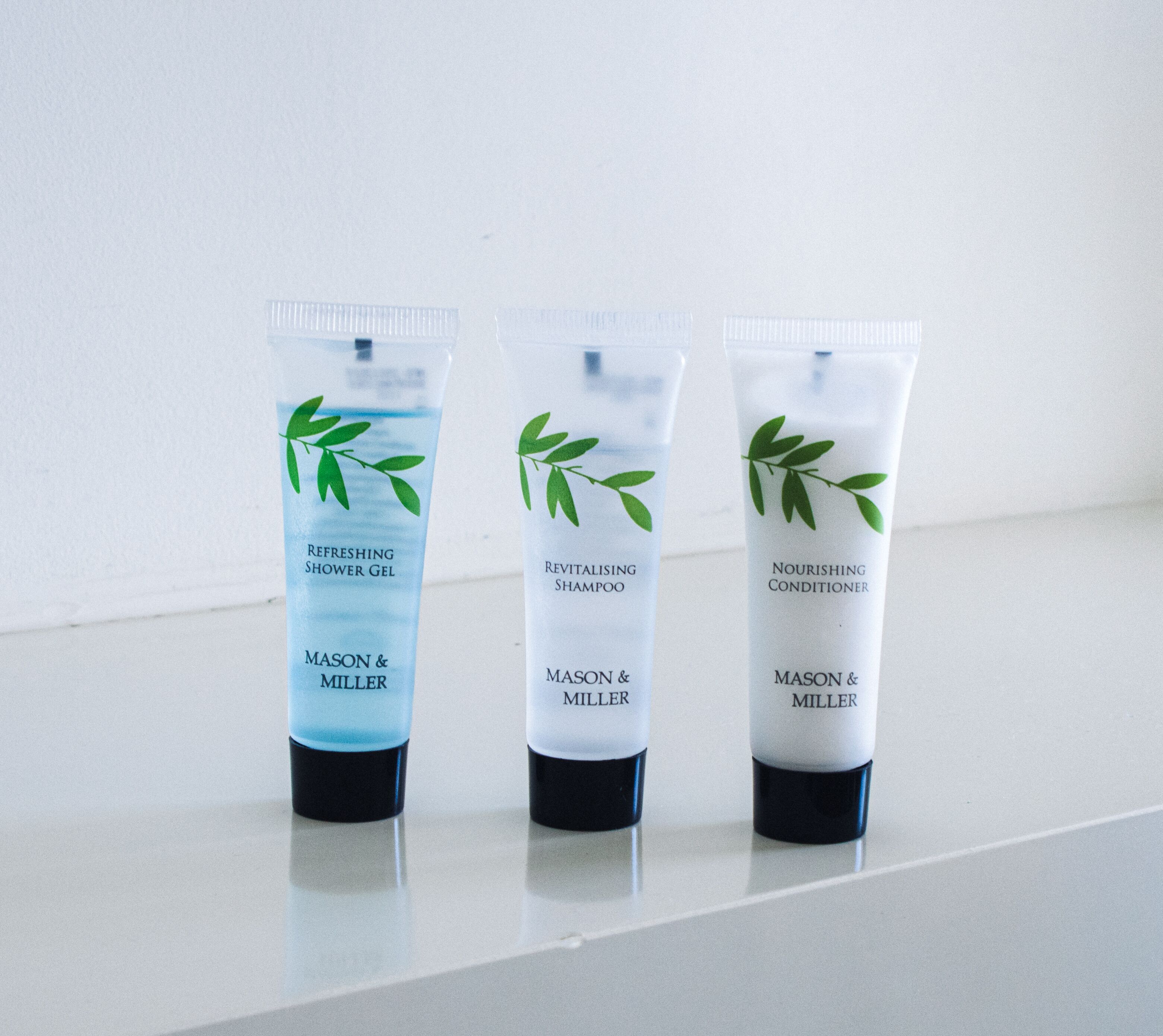 Trois produits de la marque Mason & Miller : un gel douche rafraîchissant, un shampooing revitalisant et un après-shampooing nourrissant.
