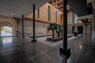 A spacious lobby with a stone wall, wooden beams, and a palm tree.