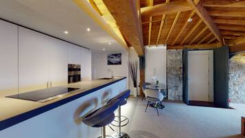 A modern kitchen with a central island, built-in oven, and a dining area with a round table and chairs.
