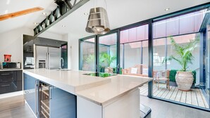 Een moderne keuken met een groot kookeiland, inbouwapparatuur en uitzicht op het terras.